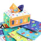Baby playing with a Montessori-inspired sensory tissue box toy, developing fine motor skills and visual focus